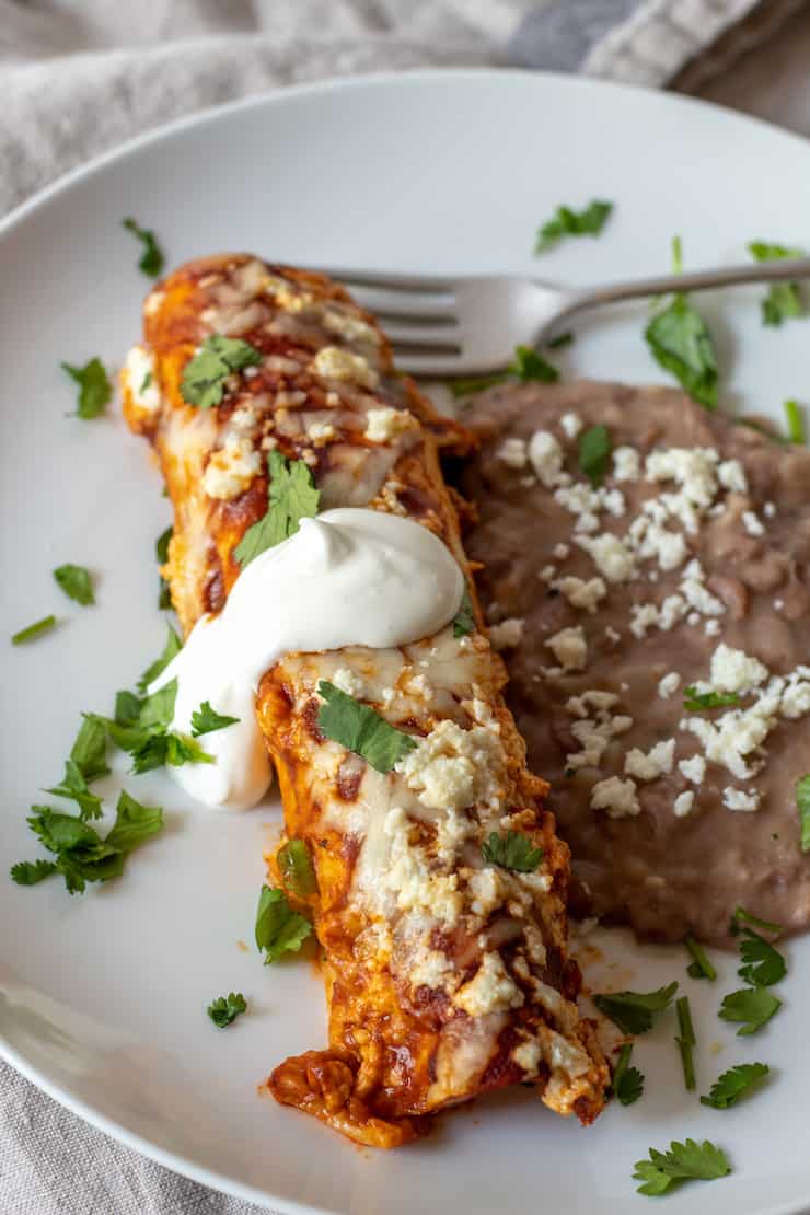 Ground turkey enchilada on plate with refried beans.