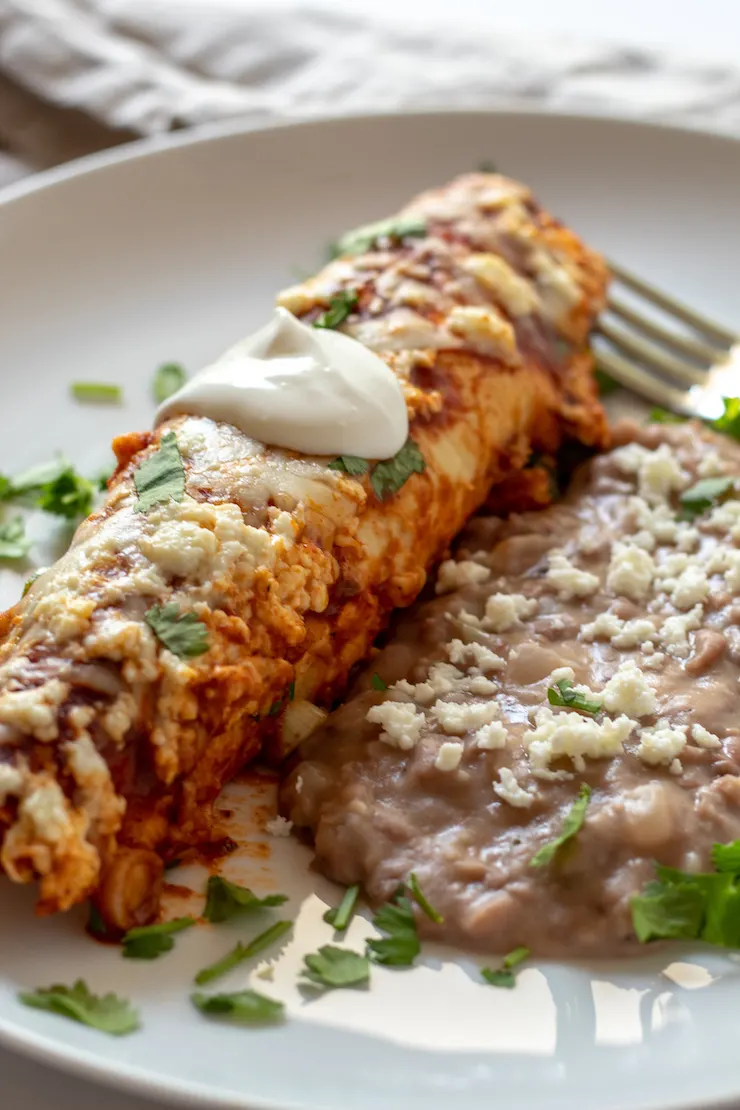 Turkey enchilada on plate with refried beans.