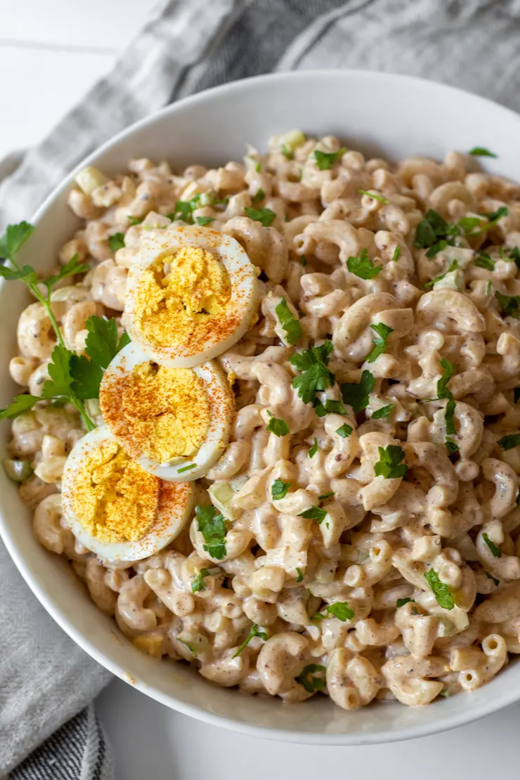 Overhead of Cajun macaroni salad in serving bowl garnished with hardboiled egg.