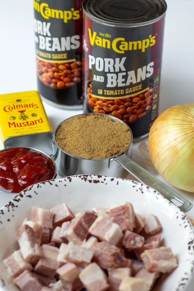 Canned pork and beans and ingredients on white board.