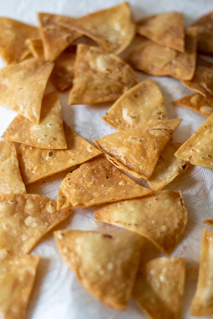 Tortilla chips draining on paper towels.