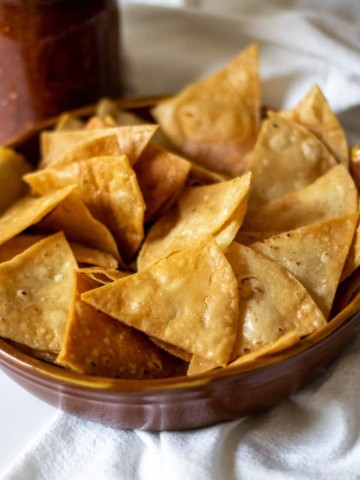 Bowl of chips with salsa in background.