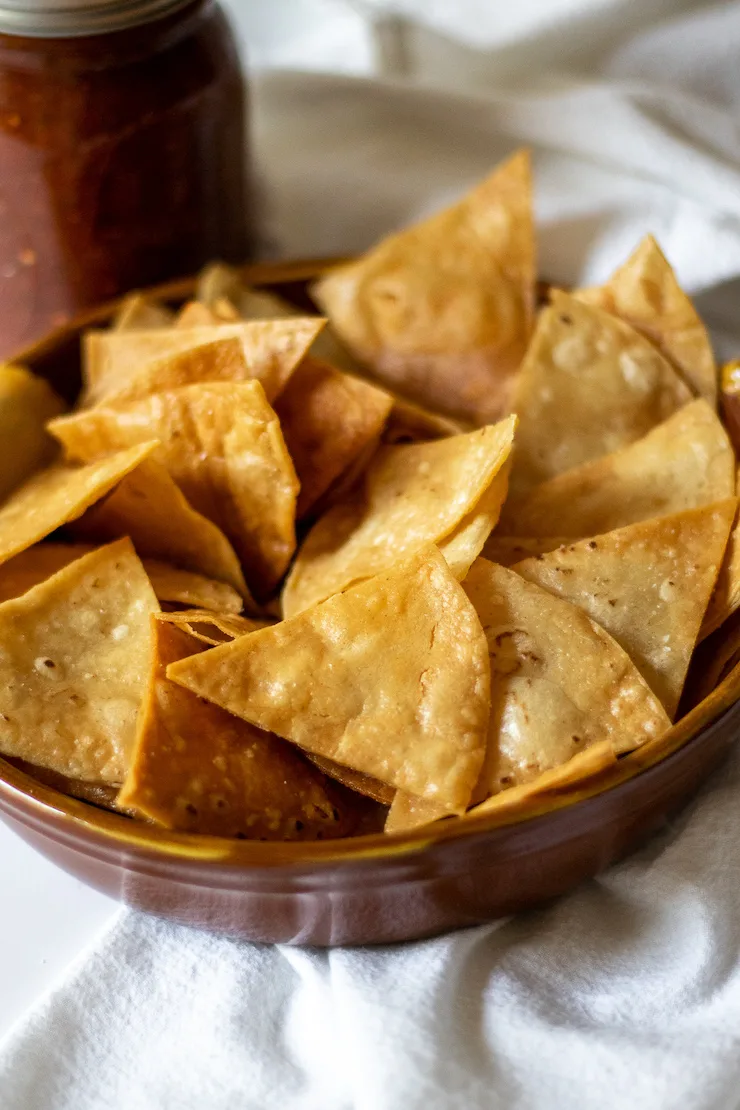 Bowl of chips with salsa in background.