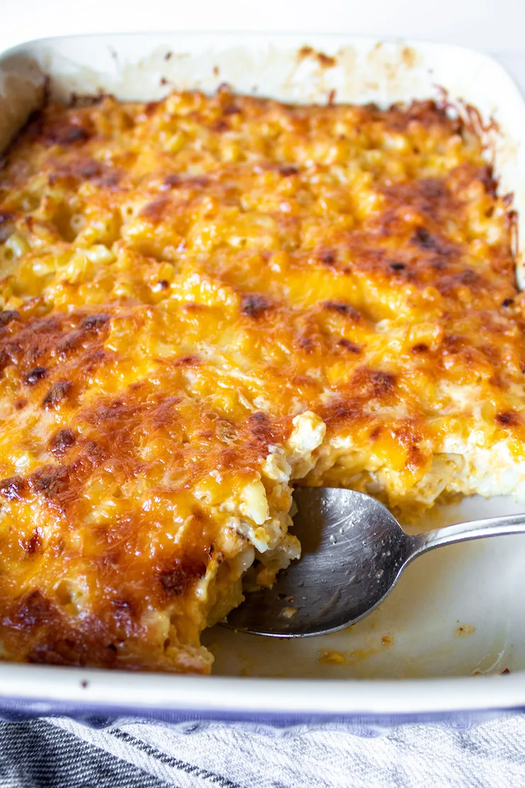 Baking dish with serving spoon in mac and cheese.