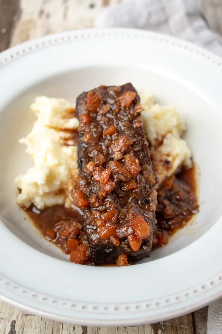 Plated Instant Pot short ribs with sauce over mashed potatoes.