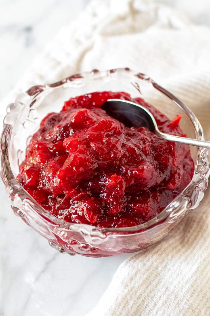 Cranberry sauce in glass serving dish with spoon.