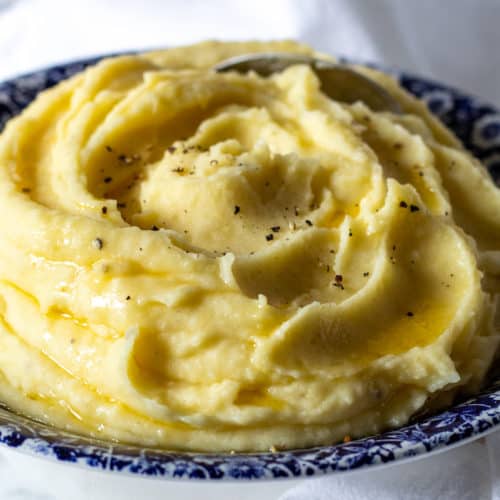 Finished mashed potatoes in blue serving bowl.