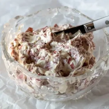 Finished dip in crystal serving bowl with serving knife.