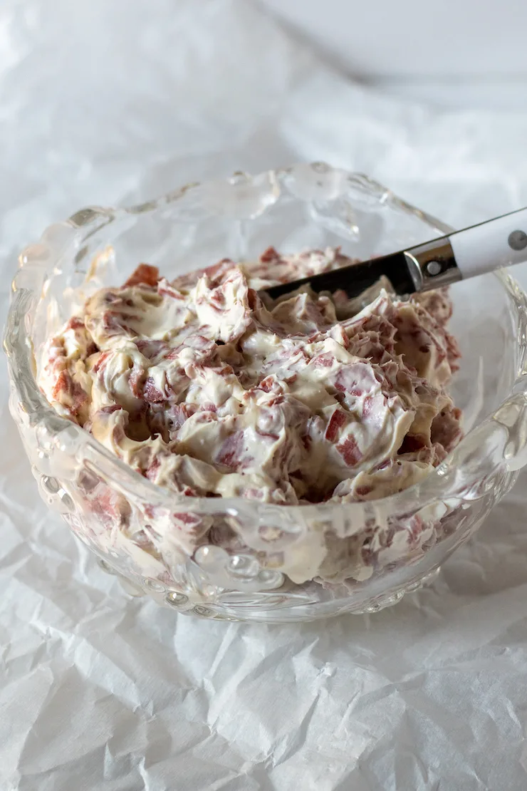 Finished chipped beef dip in crystal serving bowl with serving knife.