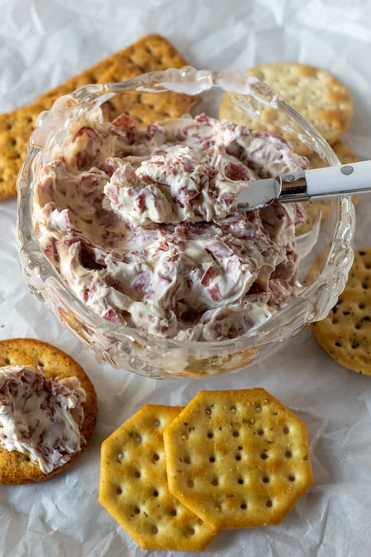 Chipped beef dip in bowl surrounded by crackers.