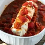 Goat cheese log and seasoned tomatoes baked in casserole dish.