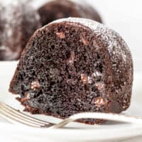 Piece of chocolate Bundt cake on white plate with fork.