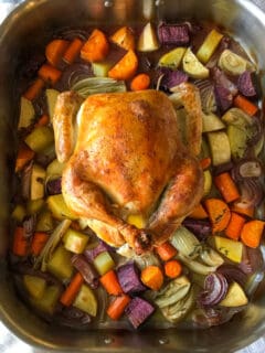 Roasted chicken over vegetables in roasting pan.
