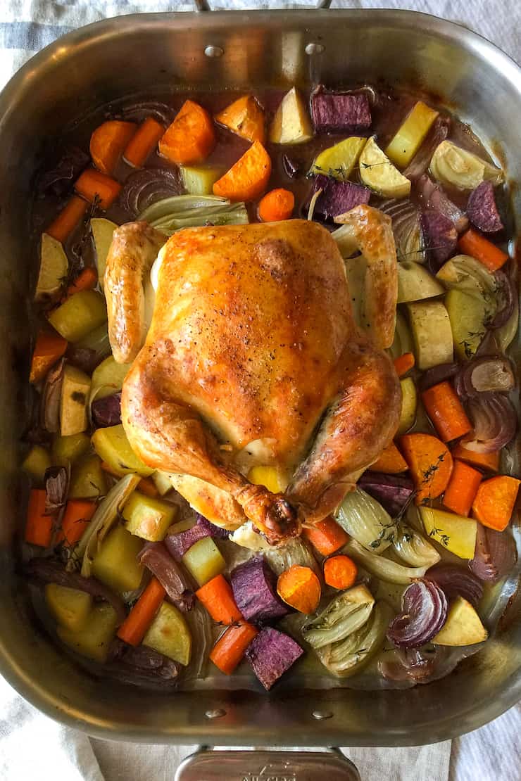 Roasted chicken over vegetables in roasting pan.