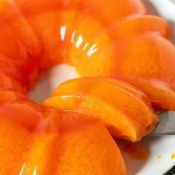 Orange sherbet jello on serving plate with serving spatula.