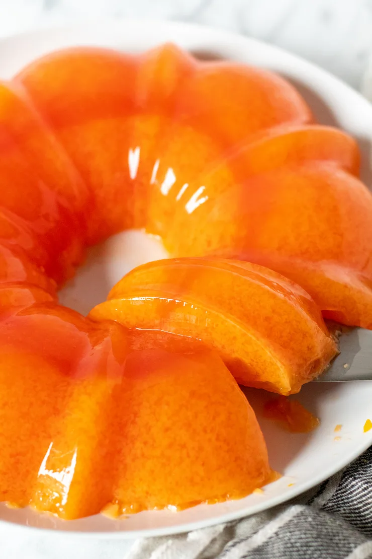 Orange sherbet jello on serving plate with serving spatula.