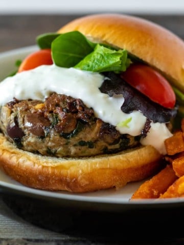 Close up of burger with sauce and lettuce and tomato.