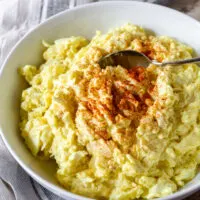 Finished potato salad in bowl with spoon and aprika.