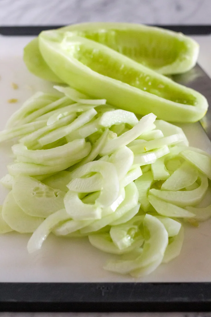 Scooping seeds out and slicing cucumbers.