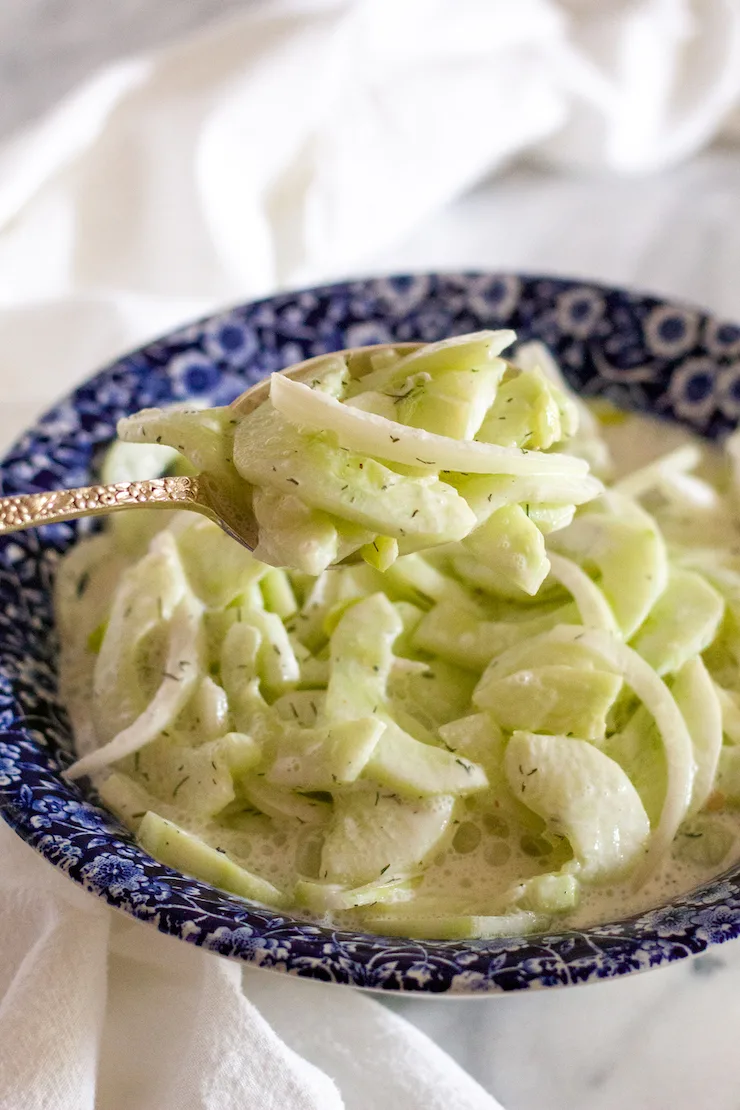 Cucumber salad in blue serving bowl.