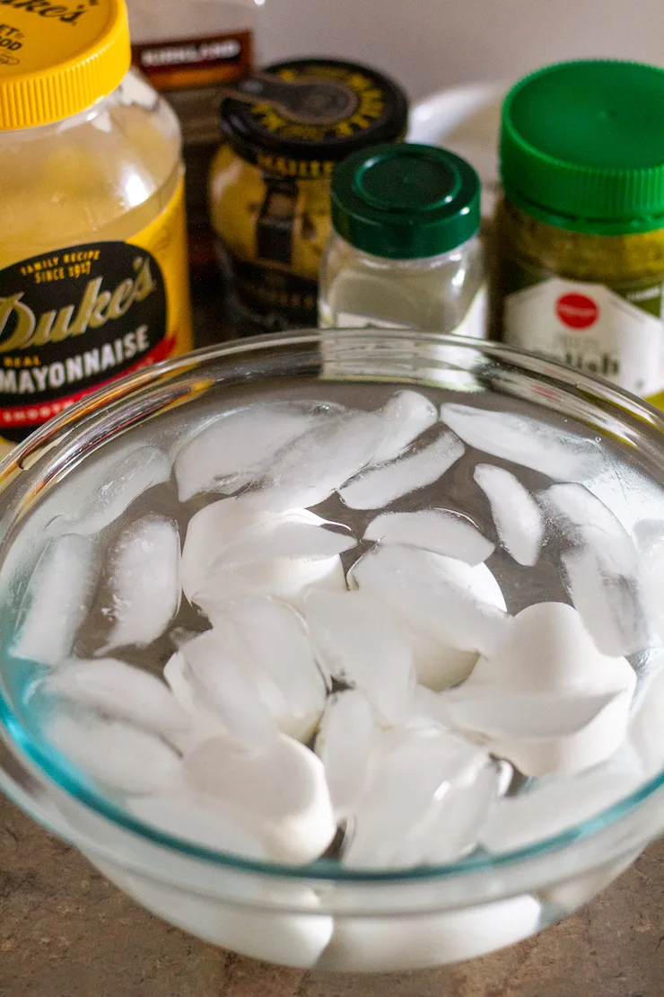 Eggs in ice water bath with ingredients in background.