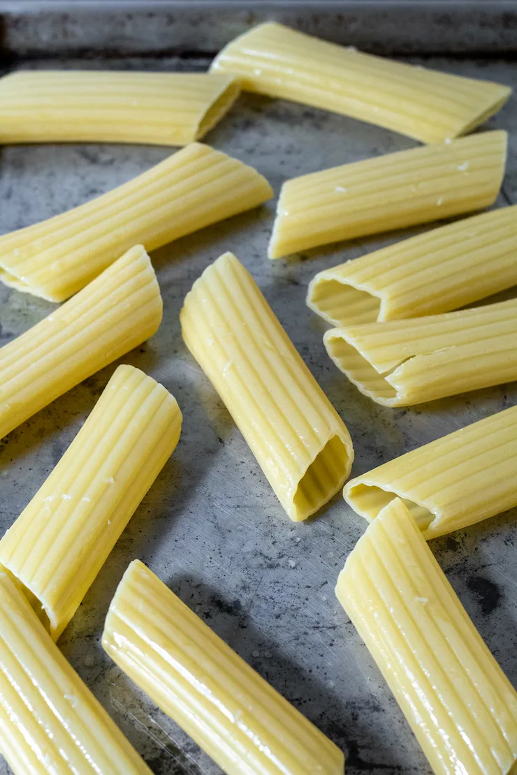 Cooked manicotti noodles cooling on sheet pan.