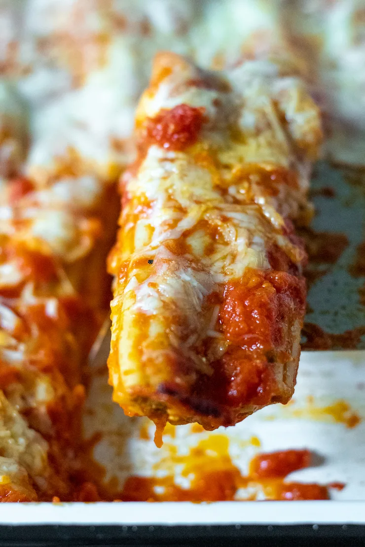 Close up of baked manicotti stuffed pasta tube.