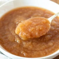 Instant Pot applesauce in white serving bowl with spoon.