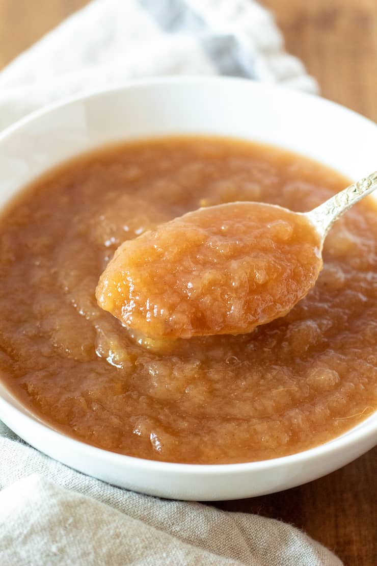 Instant Pot applesauce in white serving bowl with spoon.
