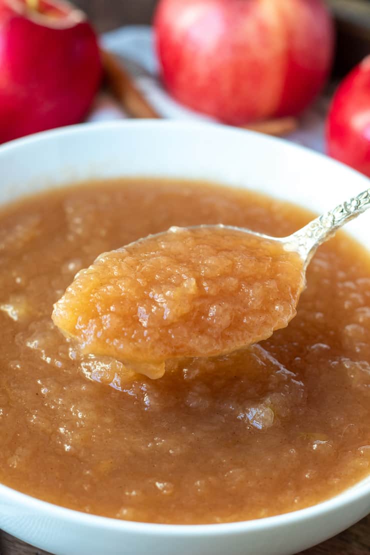 Spoonful of Instant Pot applesauce over white serving bowl.