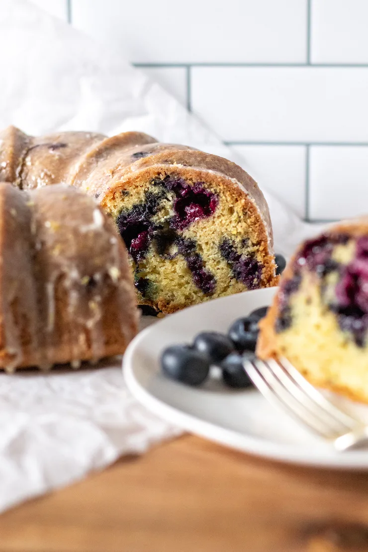 Photo of Bundt cake with slice on serving plate in the foreground.