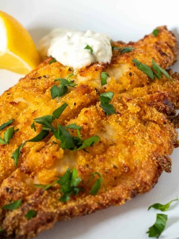 Golden brown air fryer southern catfish withhomemade tartar sauce and lemon.