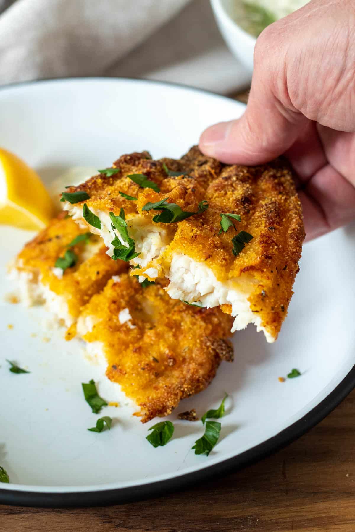 Hand holding a piece of air fryer southern catfish