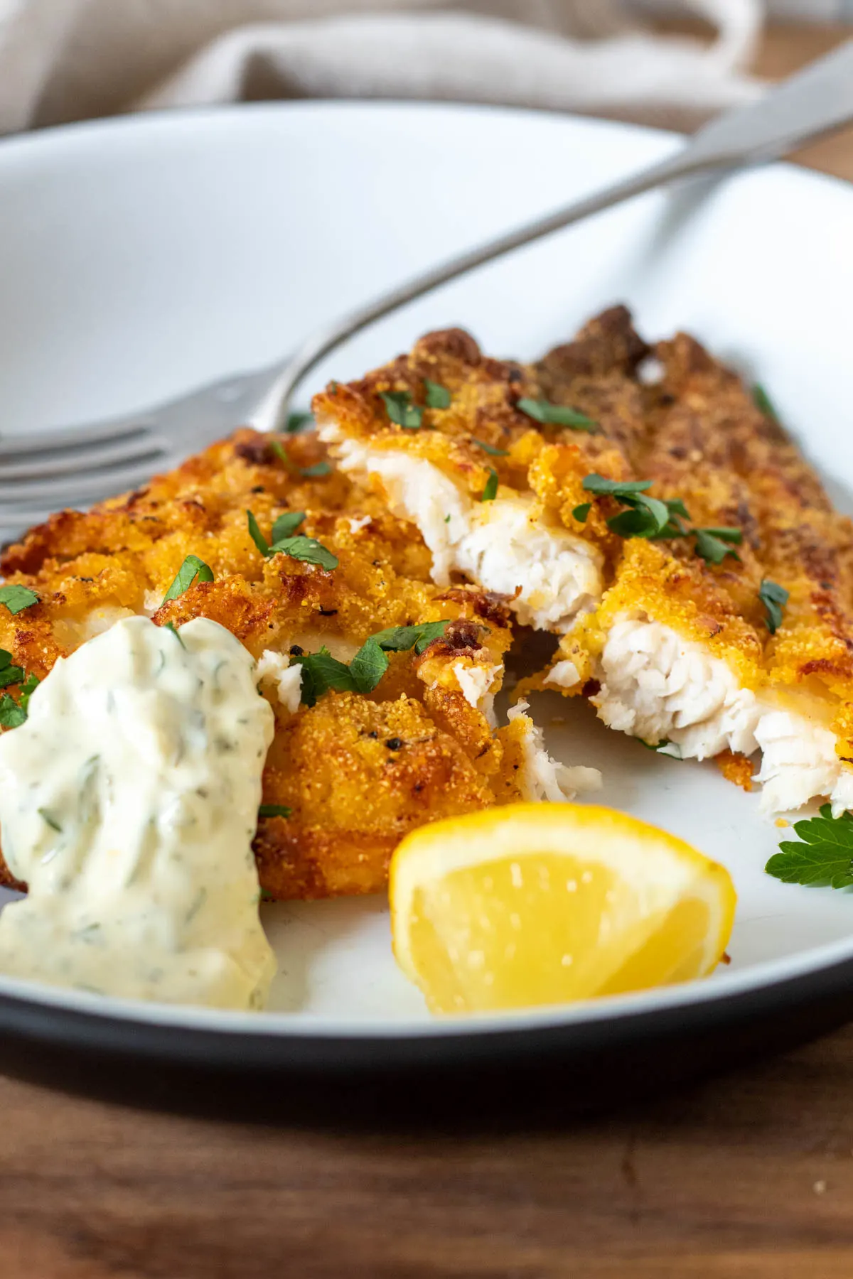 Air fryer southern catfish on plate with tartar sauce and lemon.