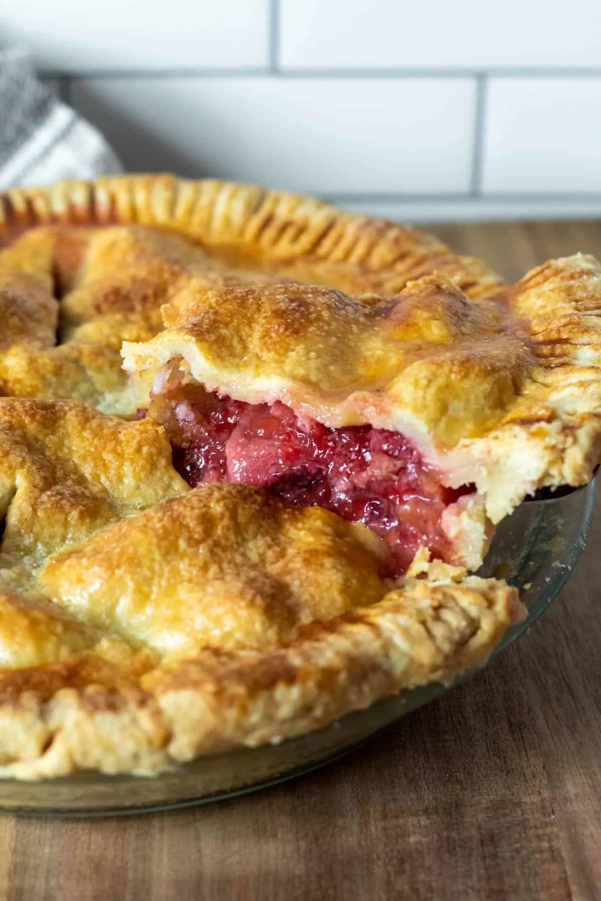 Close up of piece of strawberry rhubarb pie coming out of pie on pie server.