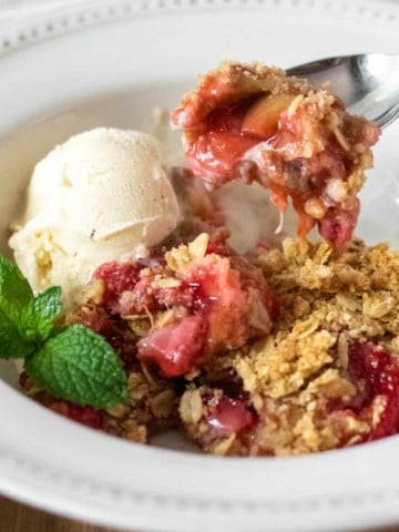 Close up in bowl with spoonful of crisp and vanilla ice cream.