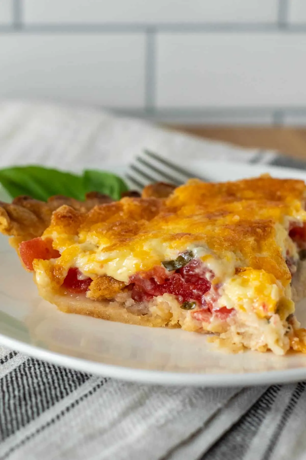 Piece of tomato pie on plate with fork.