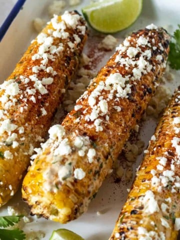Mexican street corn on platter with lime wedges