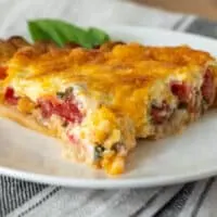 Piece of tomato pie on white serving plate.