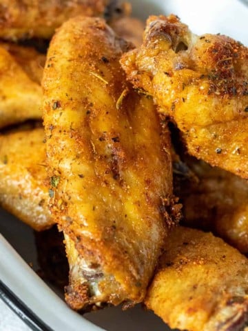 Air fryer chicken wings piled in a pan.