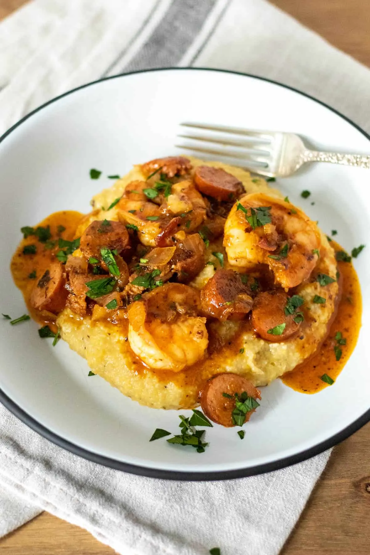 Overhead of shrimp mixture over grits on plate with fork.