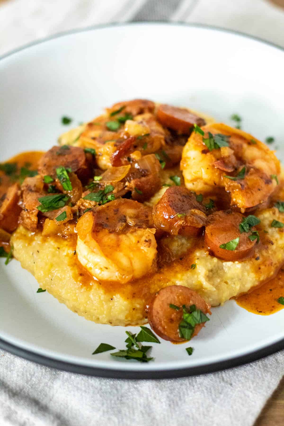 White plate with serving of shrimp and sausage mixture spooned over grits.