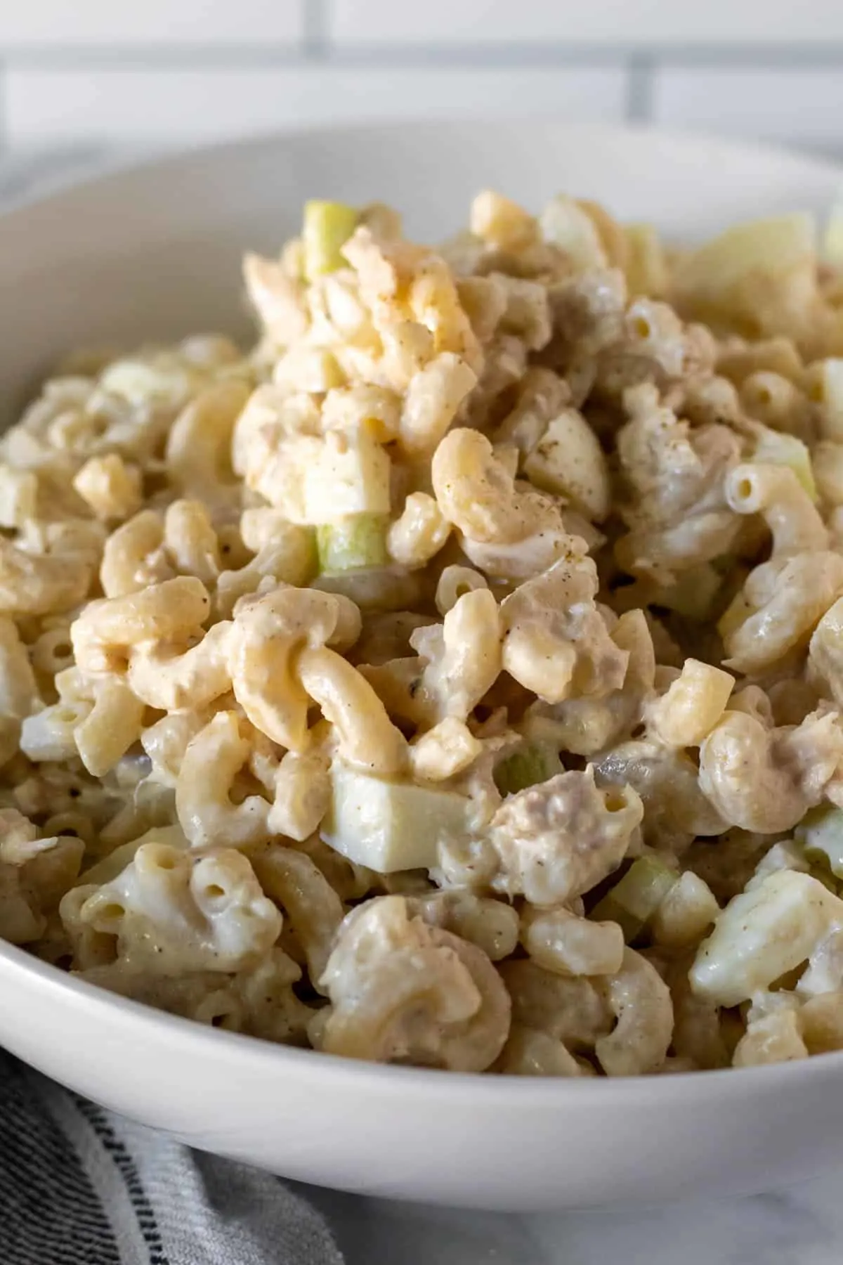 Close up of tuna macaroni salad mounded in white serving bowl.