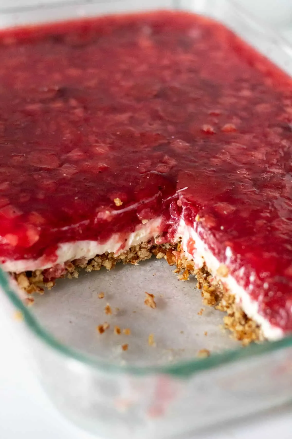 Glass baking dish of strawberry pretzel salad with section cut out showing the layers.