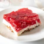 Piece of strawberry pretzel salad cut in a square on serving plate.