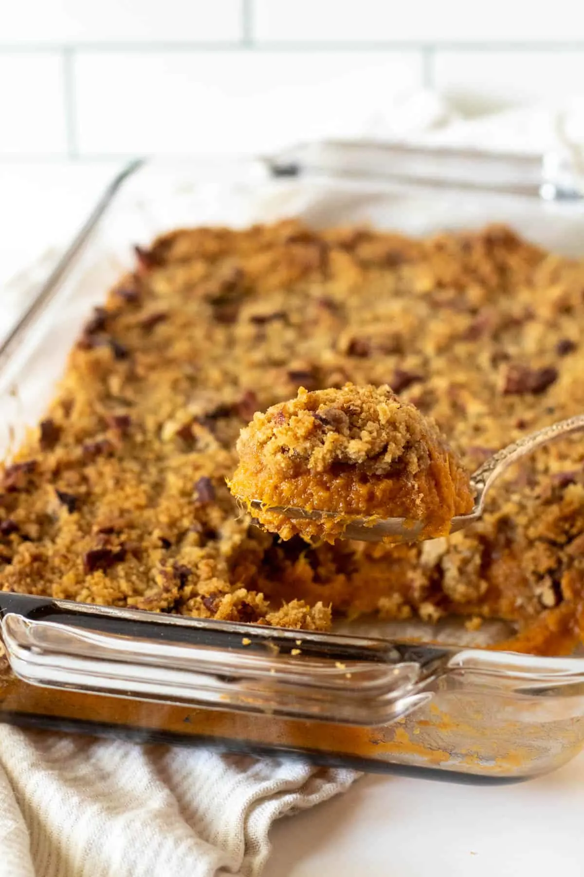 Baked sweet potato casserole with spoonful coming out of baking dish.