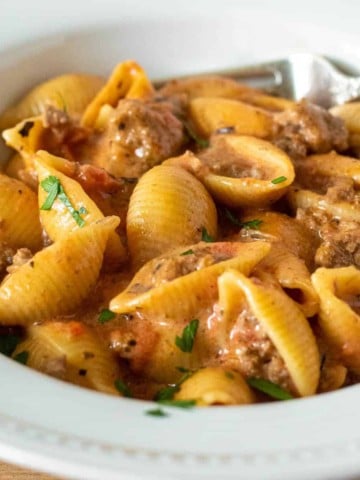 Bowl of cheesy beef and shells with fork.