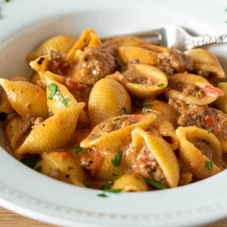 Bowl of cheesy beef and shells with fork.